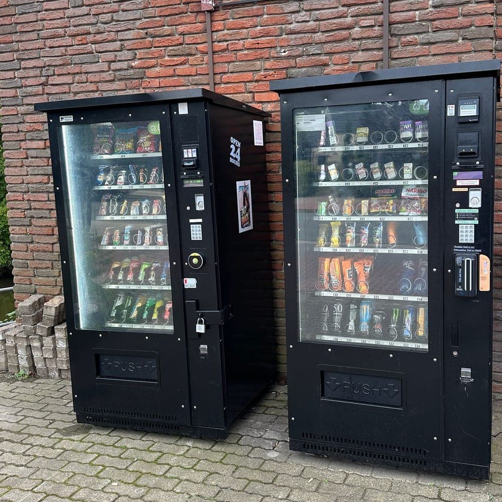 Zwei schwarze Verkaufsautomaten mit Snacks und Getränken an der Klinkerwand vor der Diskothek M2